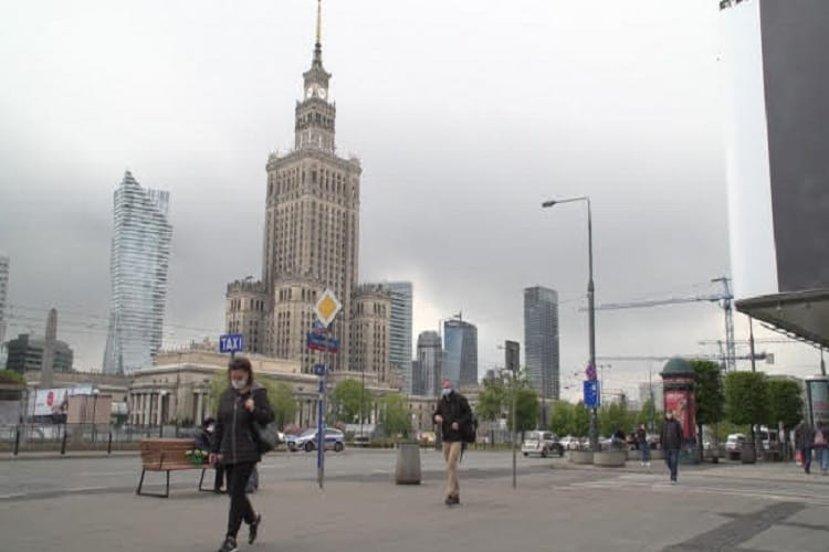 Panorama Warszawy z Pałacem Kultury i Nauki i pieszymi w maskach.