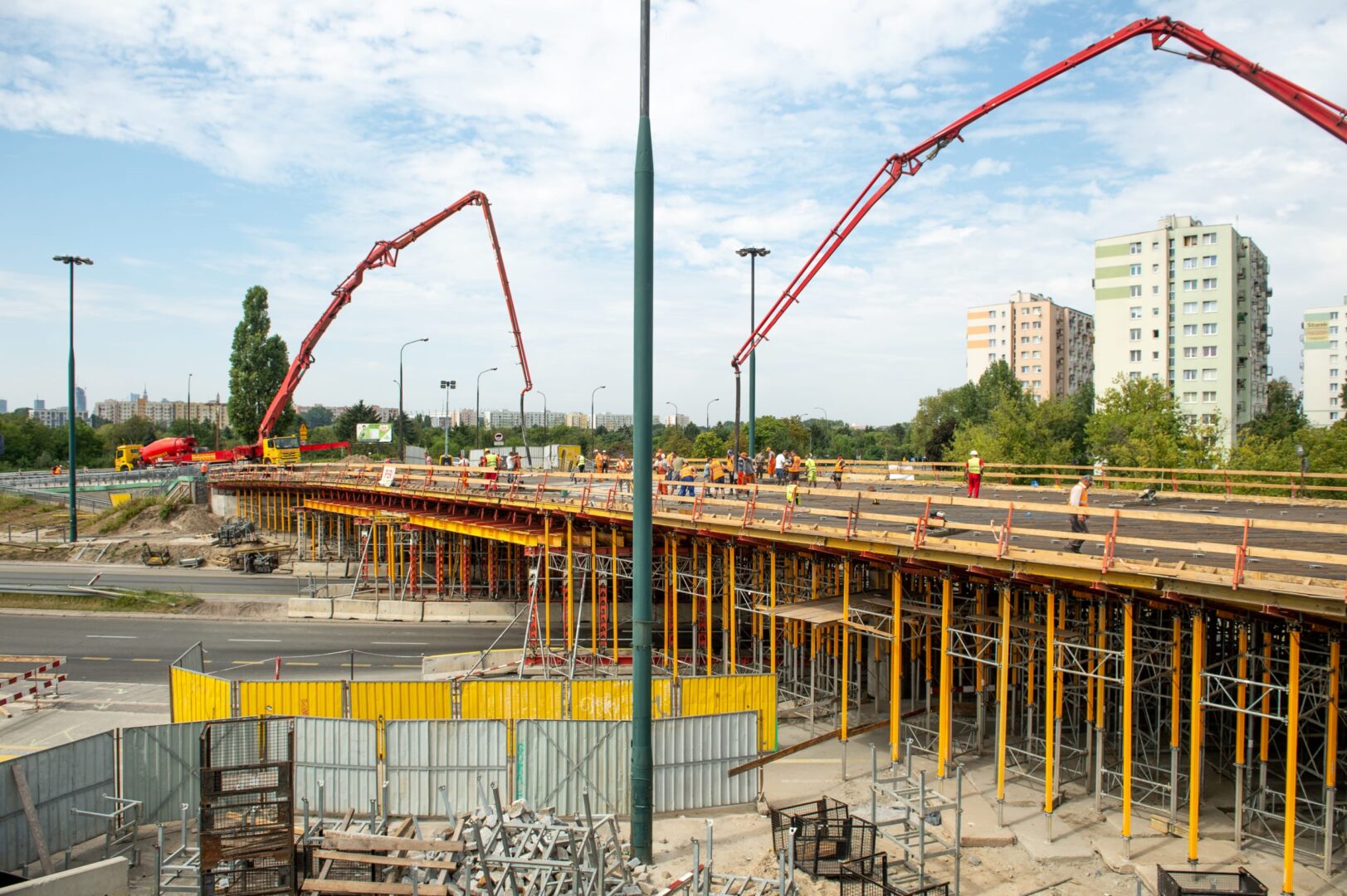 Robotnicy budowlani wylewają beton na nowy most za pomocą betoniarek.