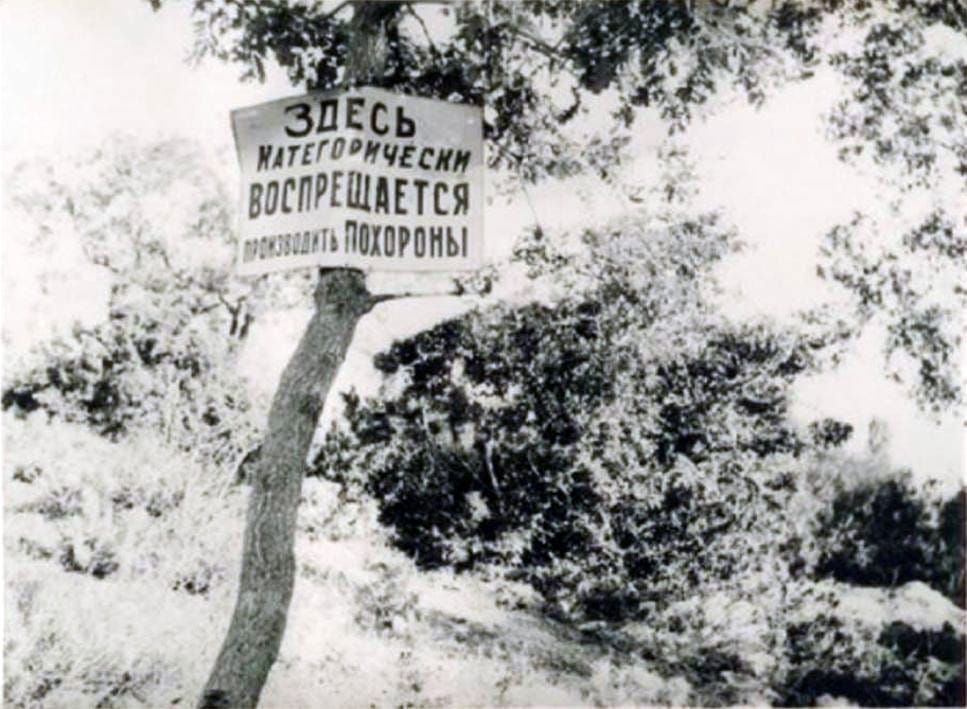 Czarno-białe zdjęcie tabliczki zabraniającej pochówku z napisem „Здесь категорически воспрещается производить похороны.