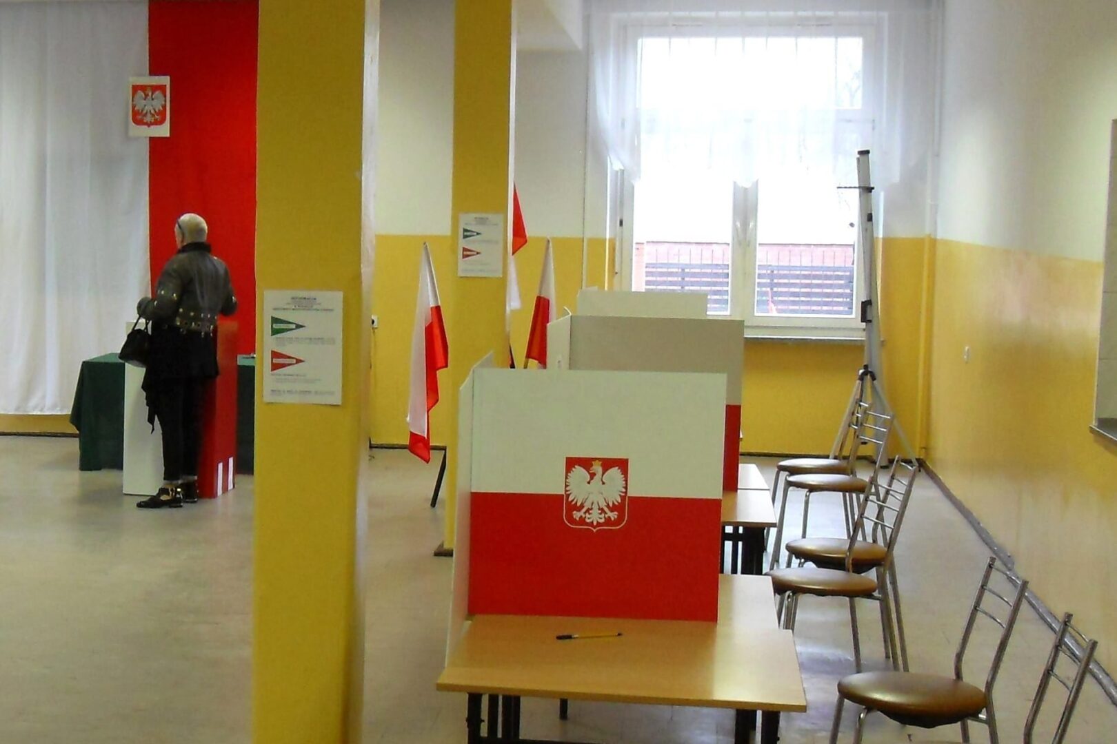 Wnętrze lokalu wyborczego w Polsce. Wyborcy oddają głosy.