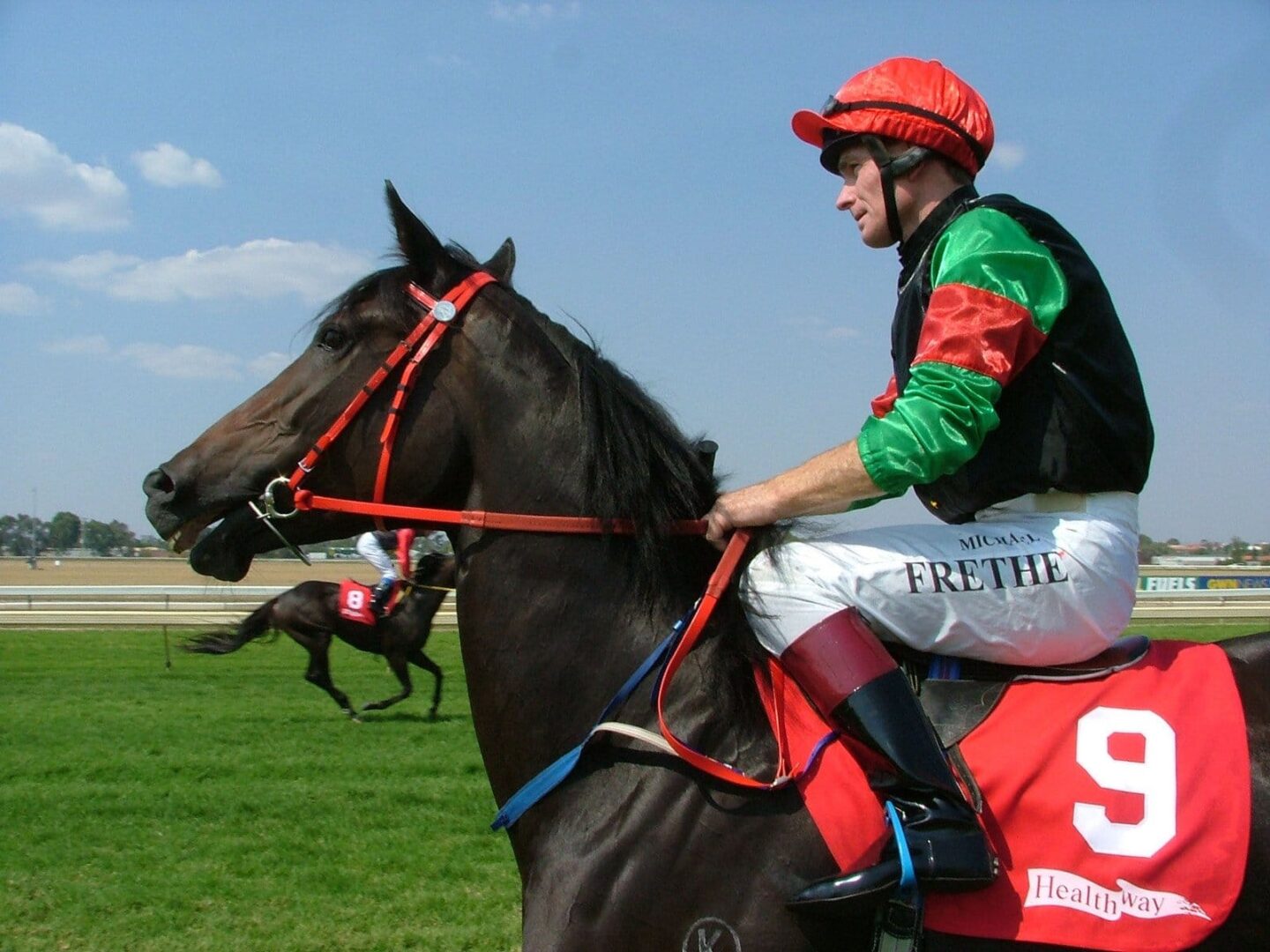 Dżokej na czarnym koniu wyścigowym z numerem 9 i napisem „Fre the” na bryczesach