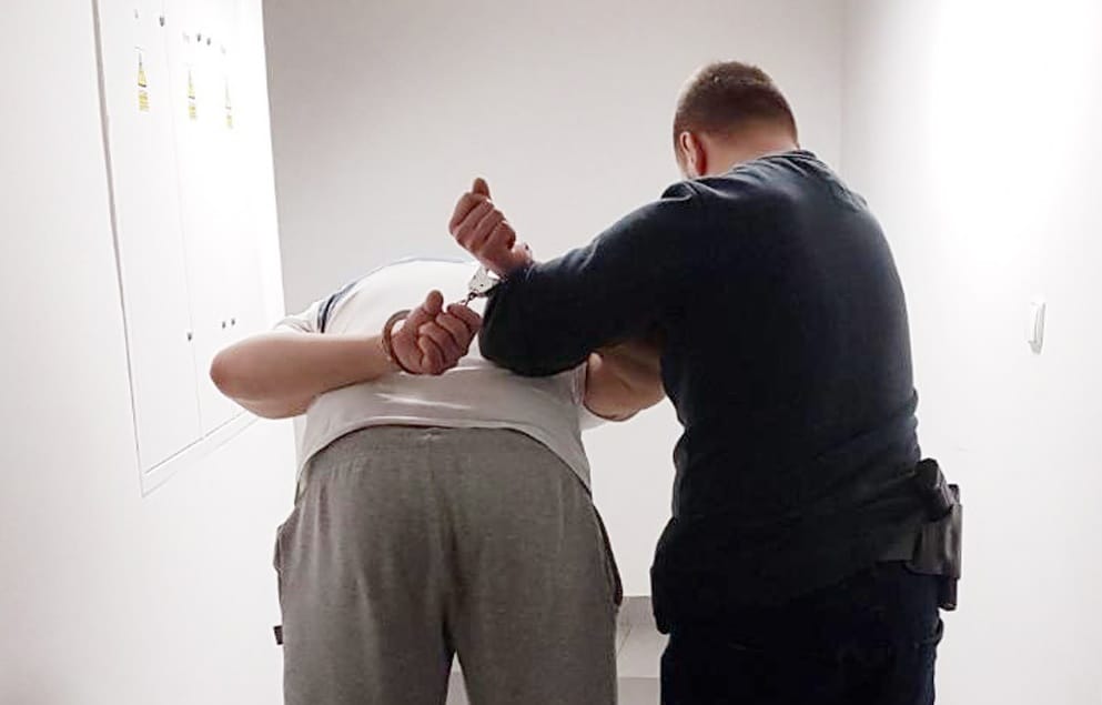Policjant zakładający podejrzanemu kajdanki.