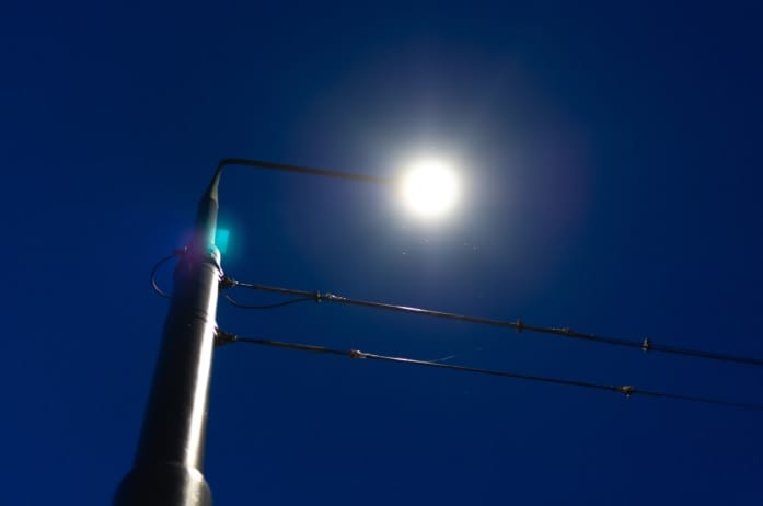 Widok latarni ulicznej z dołu na tle jasnoniebieskiego nieba.