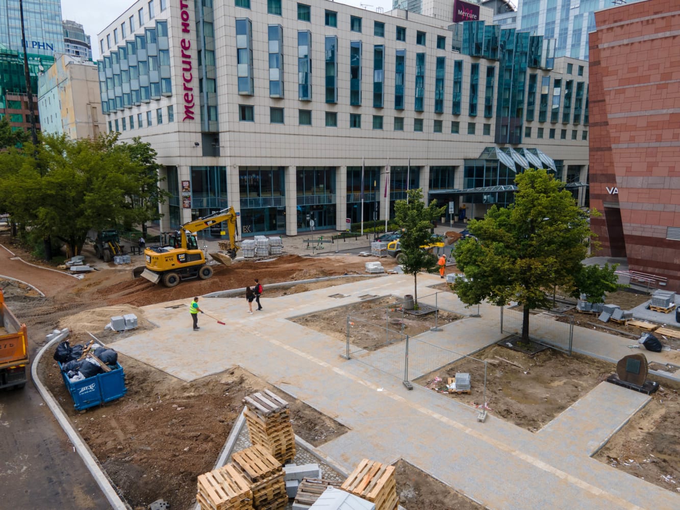 Widok z lotu ptaka na plac budowy w pobliżu hotelu Mercure. Robotnicy i maszyny wytyczają nowe chodniki.