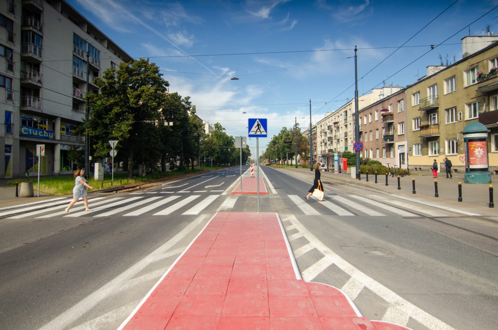 Piesi przechodzący przez ulicę miejską z czerwonym pasem rowerowym
