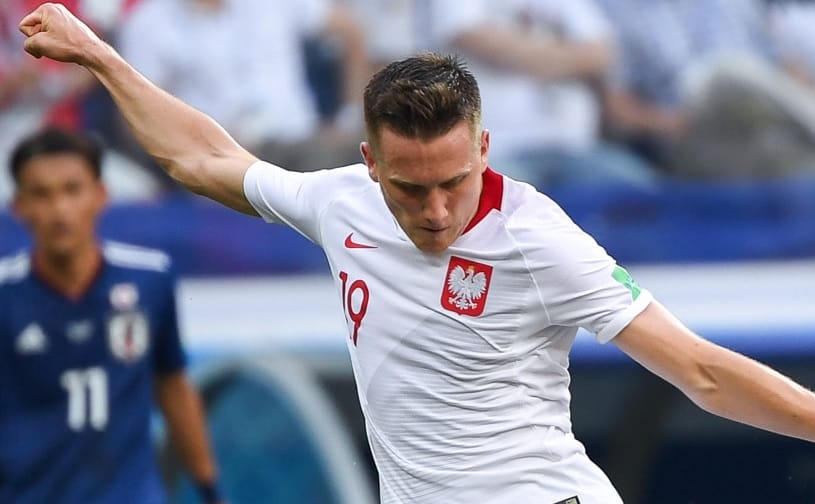 Polski piłkarz Robert Lewandowski świętuje gola, mając na sobie białą koszulkę swojej drużyny z numerem 10.