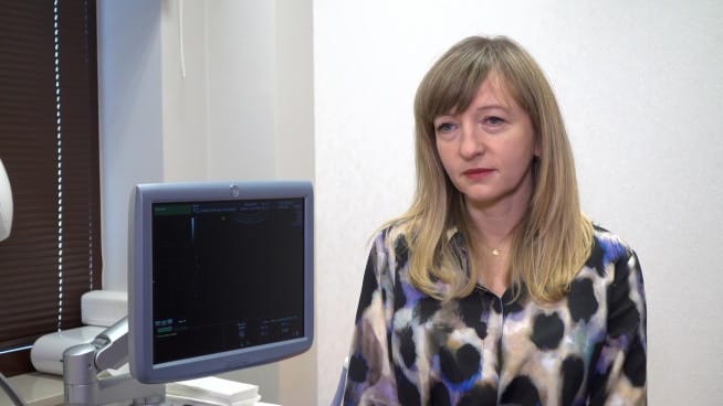 Lekarka we wzorzystej bluzce omawia wyniki badania USG na monitorze.