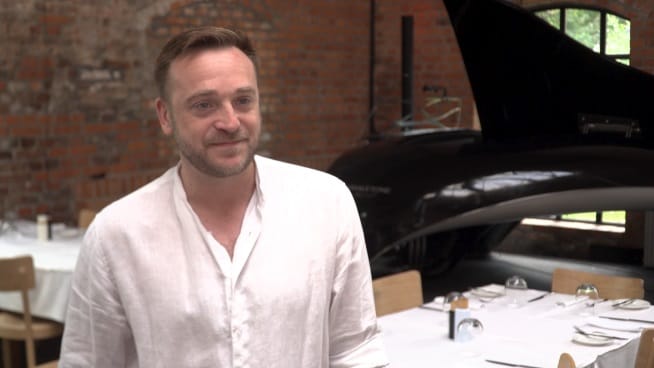 Mężczyzna w białej koszuli uśmiechający się w restauracji