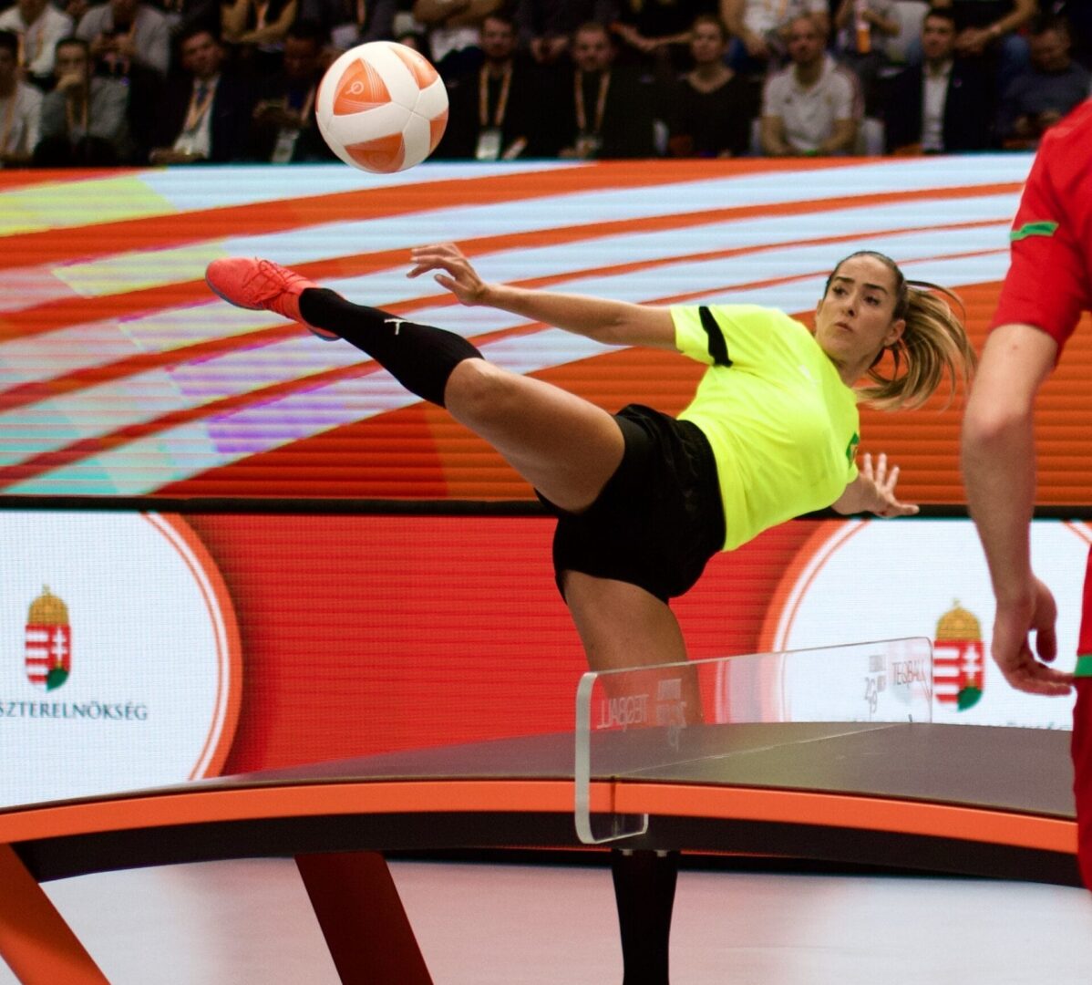 Zawodniczka teqballu wykonuje efektowny kop, posyłając piłkę ponad siatkę.