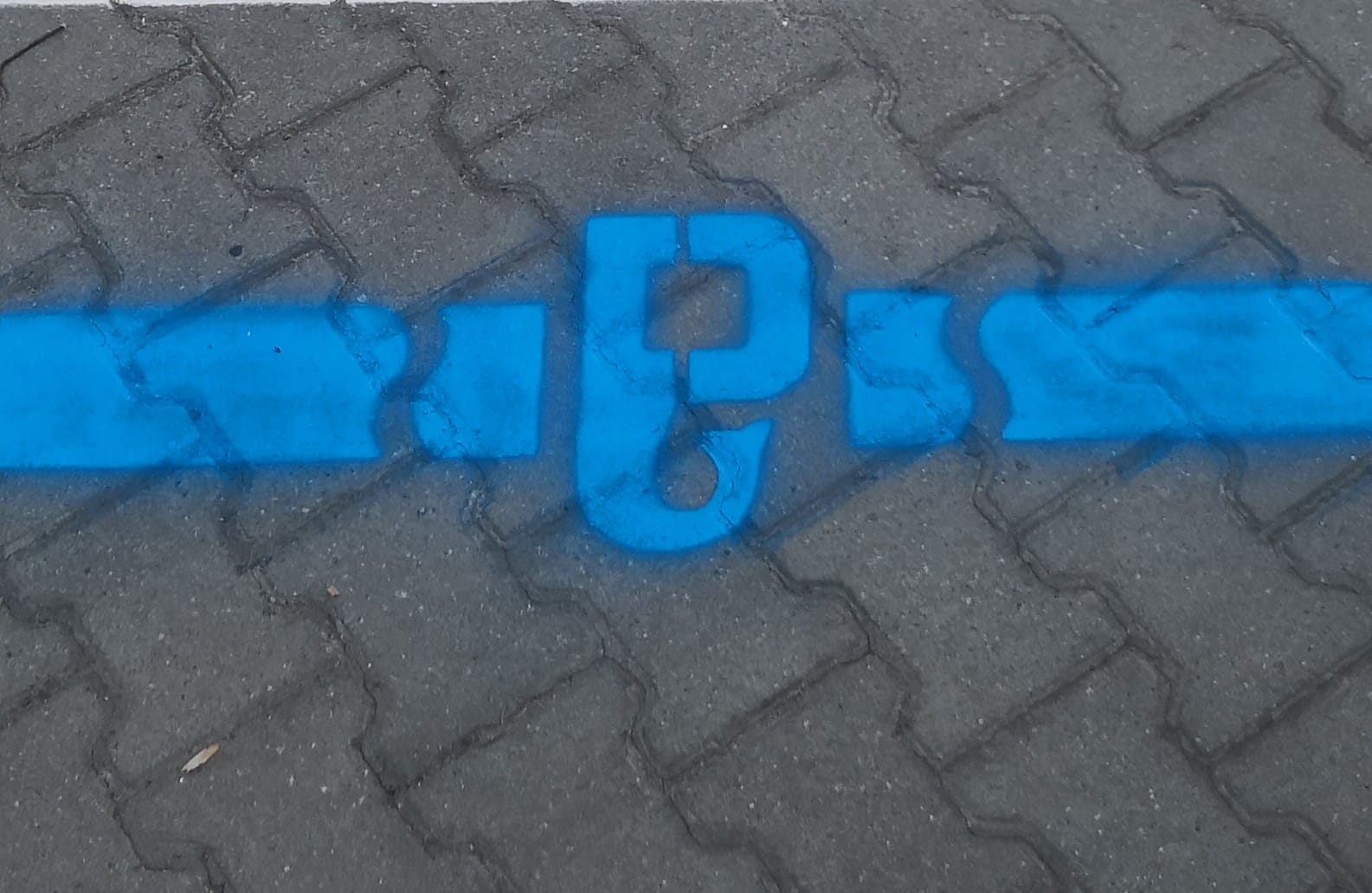 Niebieskie oznakowanie nawierzchni symbolem haka wskazujące na instalacje podziemne.