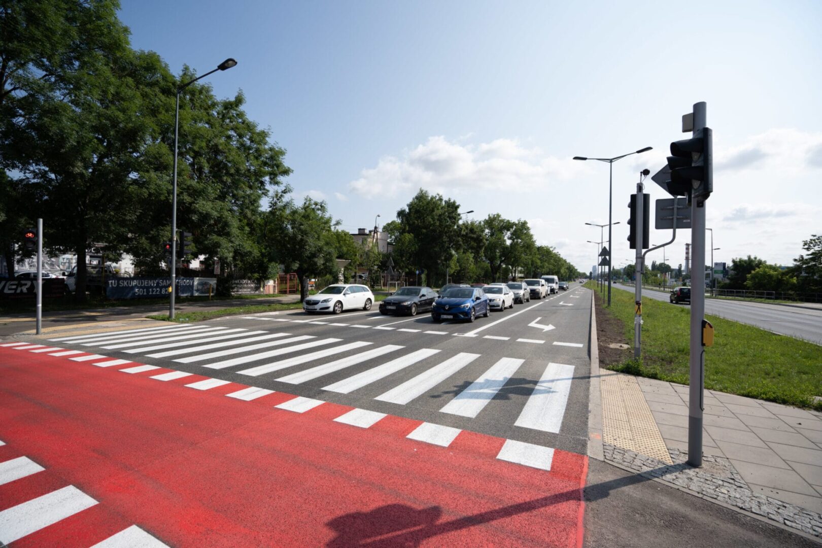 Przejście dla pieszych z czerwonym pasem rowerowym i samochody zatrzymane na światłach