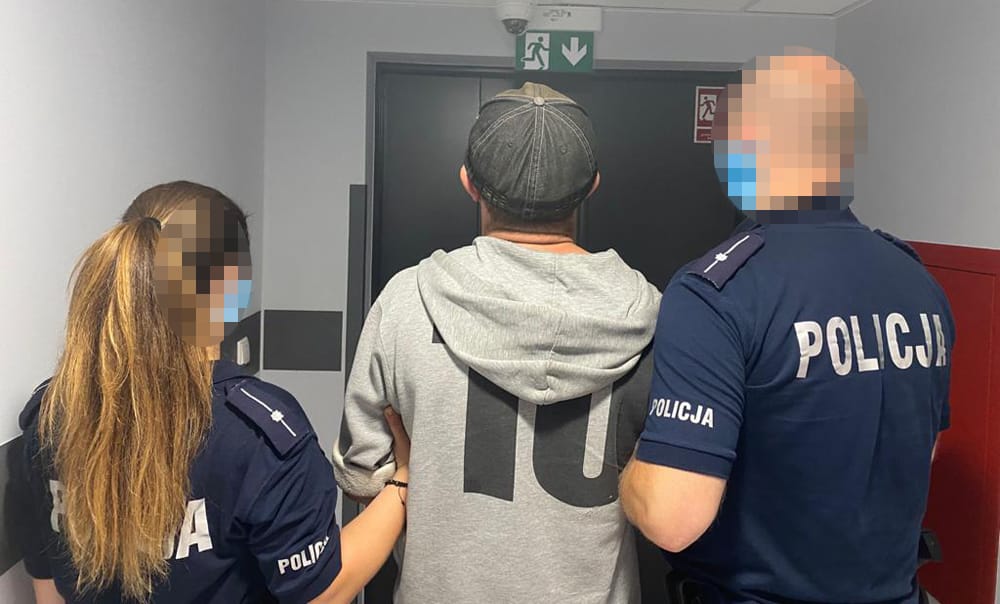 Policjanci aresztujący podejrzanego. Na ich mundurach widać słowo „POLICJA”.