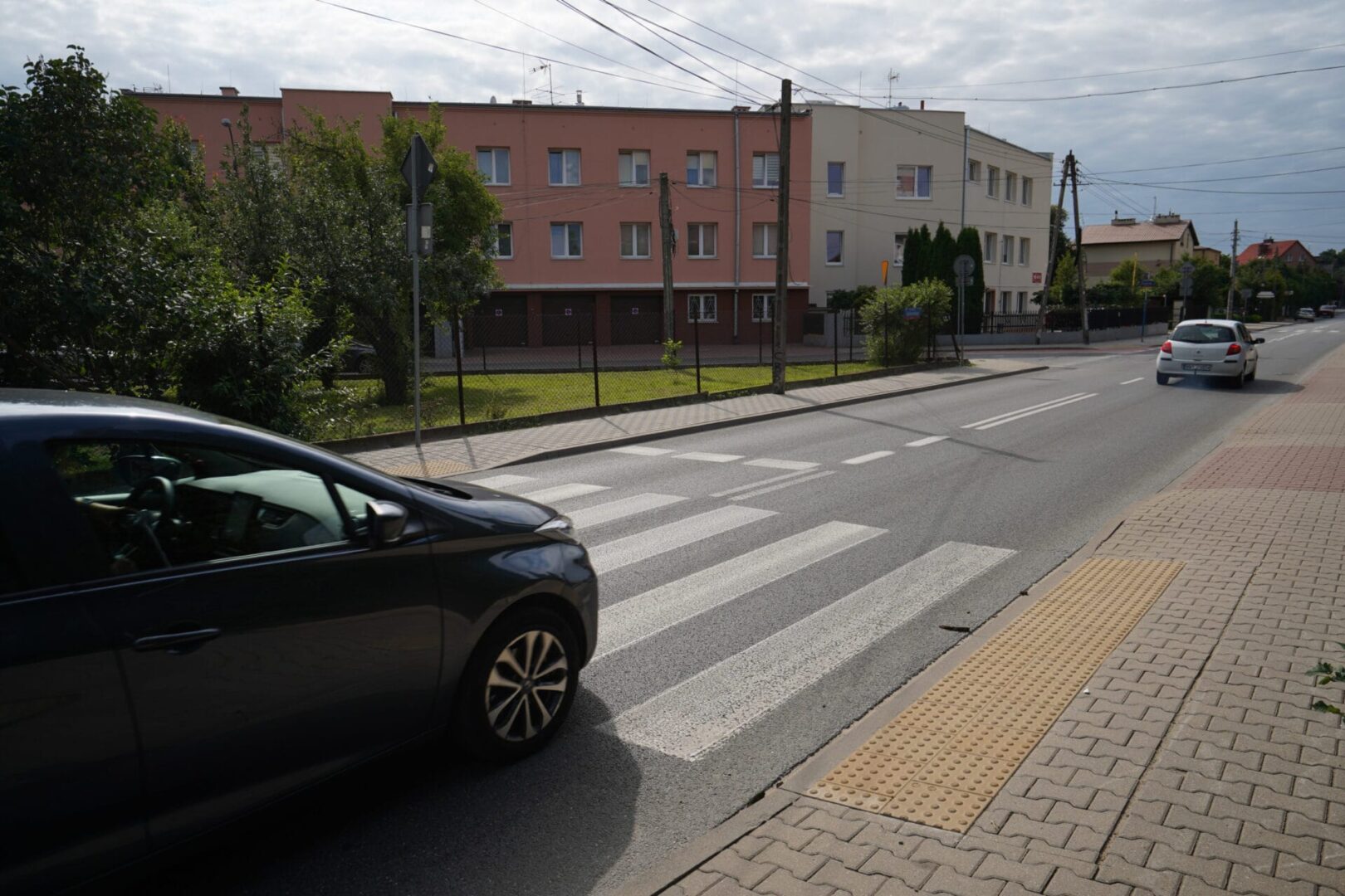 Samochód zbliżający się do przejścia dla pieszych w pobliżu budynków mieszkalnych