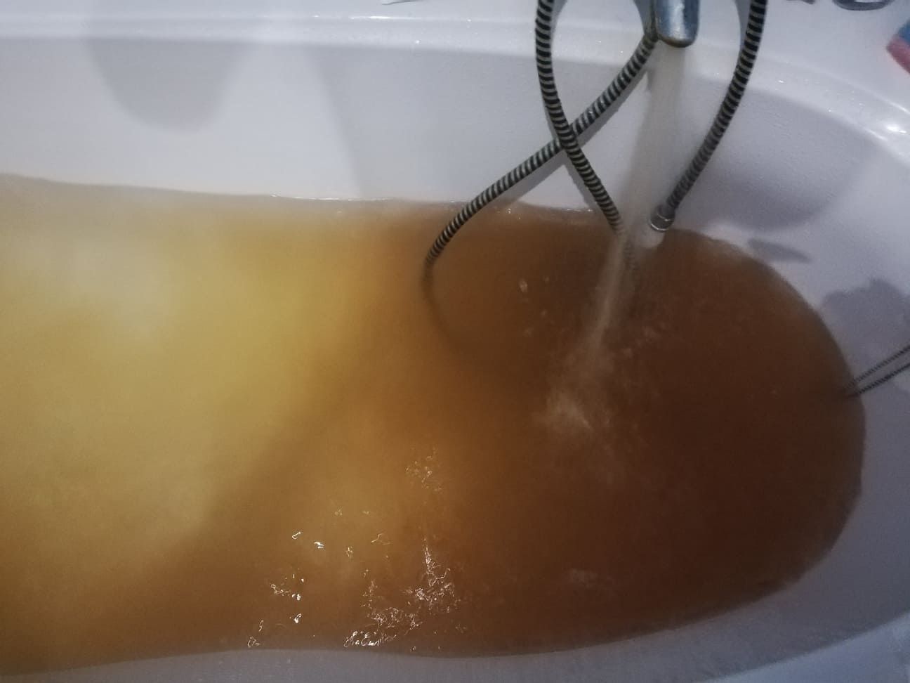 Brązowa, mętna woda wypełnia wannę, wypływa z kranu. Przebarwienie wody.