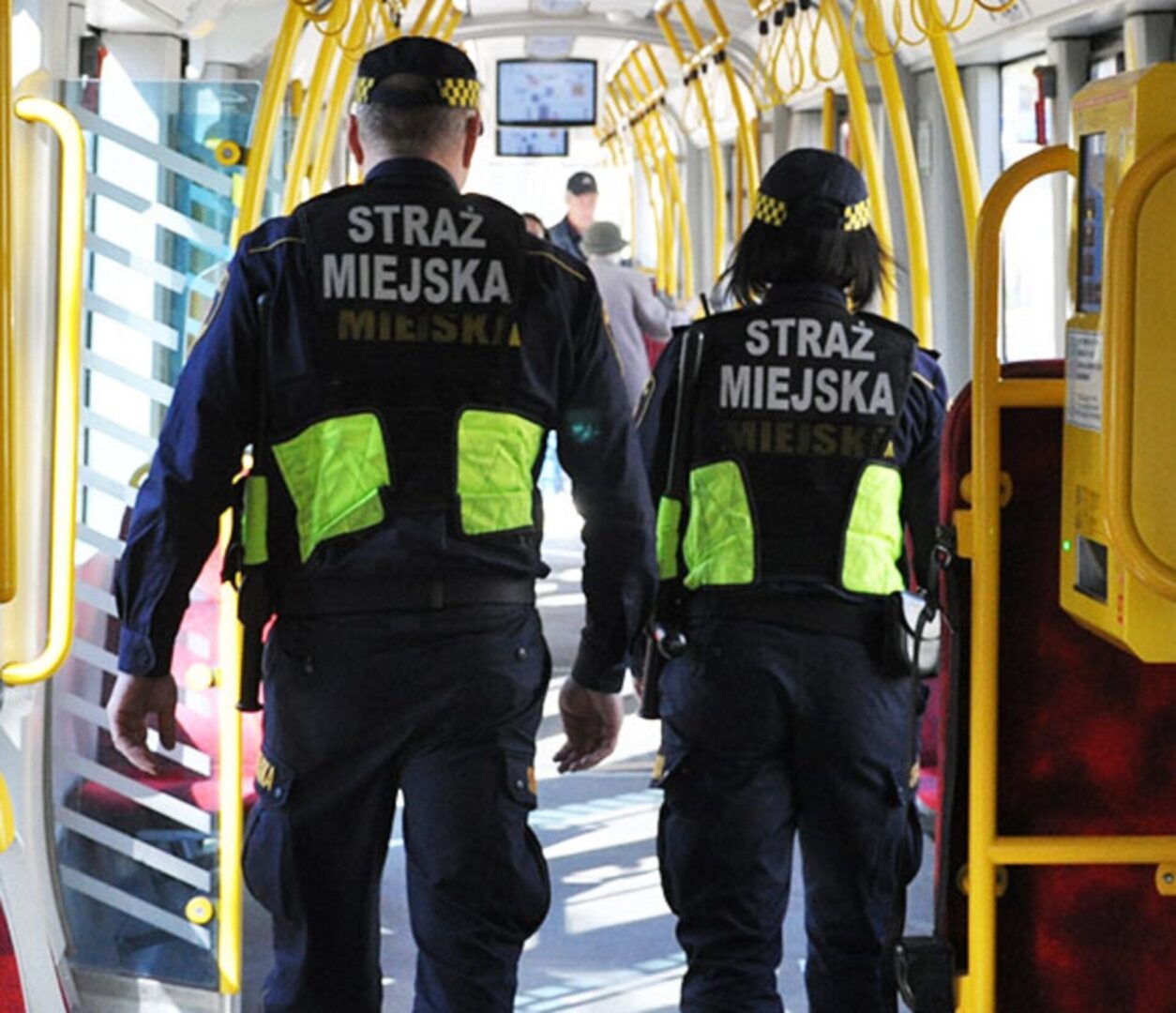 Dwóch polskich Strażników Miejskich w tramwaju komunikacji miejskiej.
