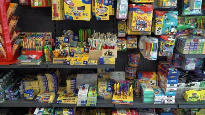 Dobrze zaopatrzona półka ugina się od kolorowych przyborów artystycznych, w tym kredek, markerów, pędzli i papieru budowlanego.