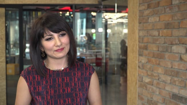 Zdjęcie kobiety o ciemnych włosach, ubranej we wzorzystą sukienkę.