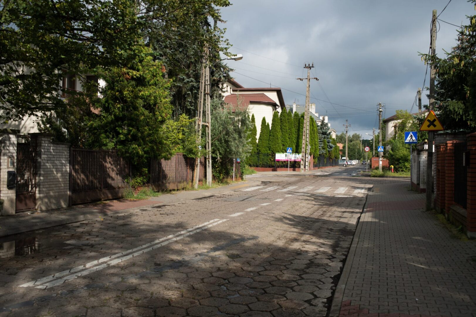 Spokojna ulica mieszkalna w Polsce z brukowaną drogą i domami.