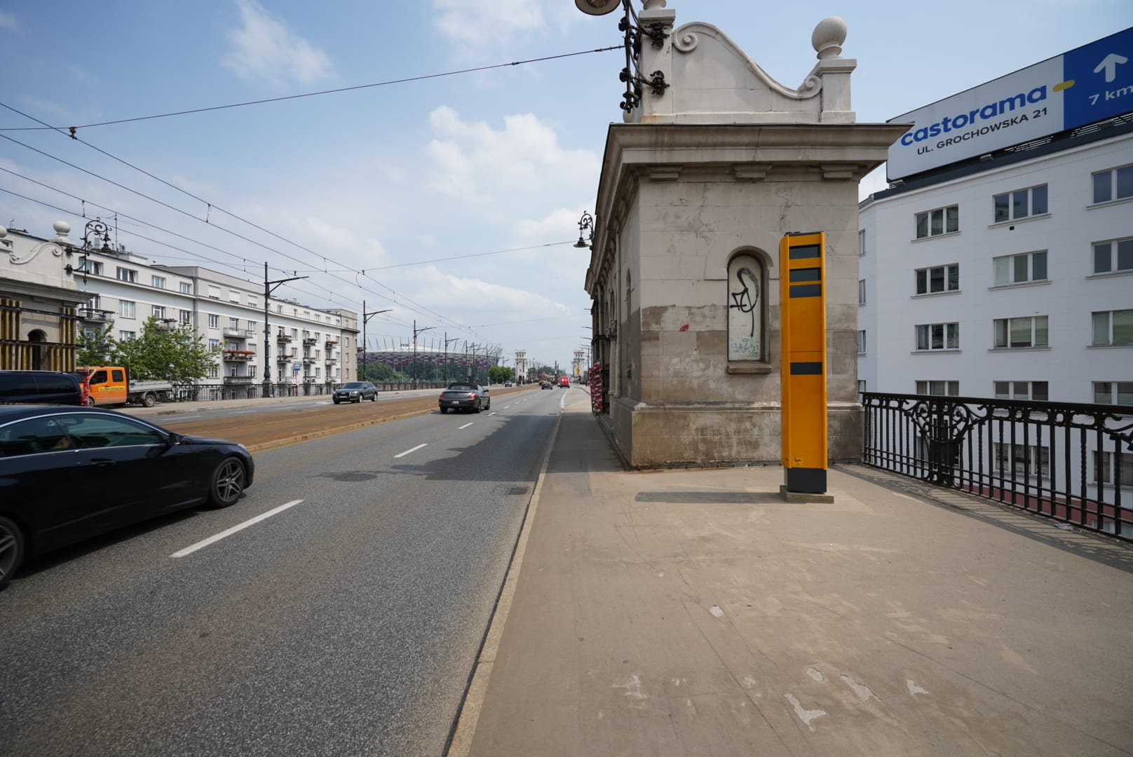 Scena uliczna Warszawy: samochody na moście, nowoczesny budynek ze znakiem Castorama