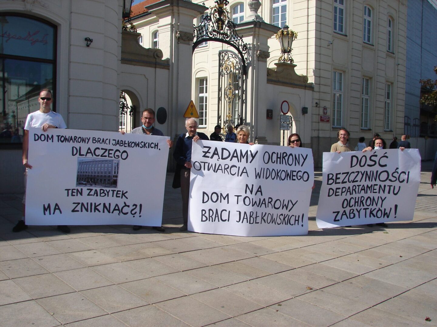 Protestujący trzymają transparenty domagające się ochrony i ponownego otwarcia zabytkowego domu towarowego Jabłkowski Brothers.