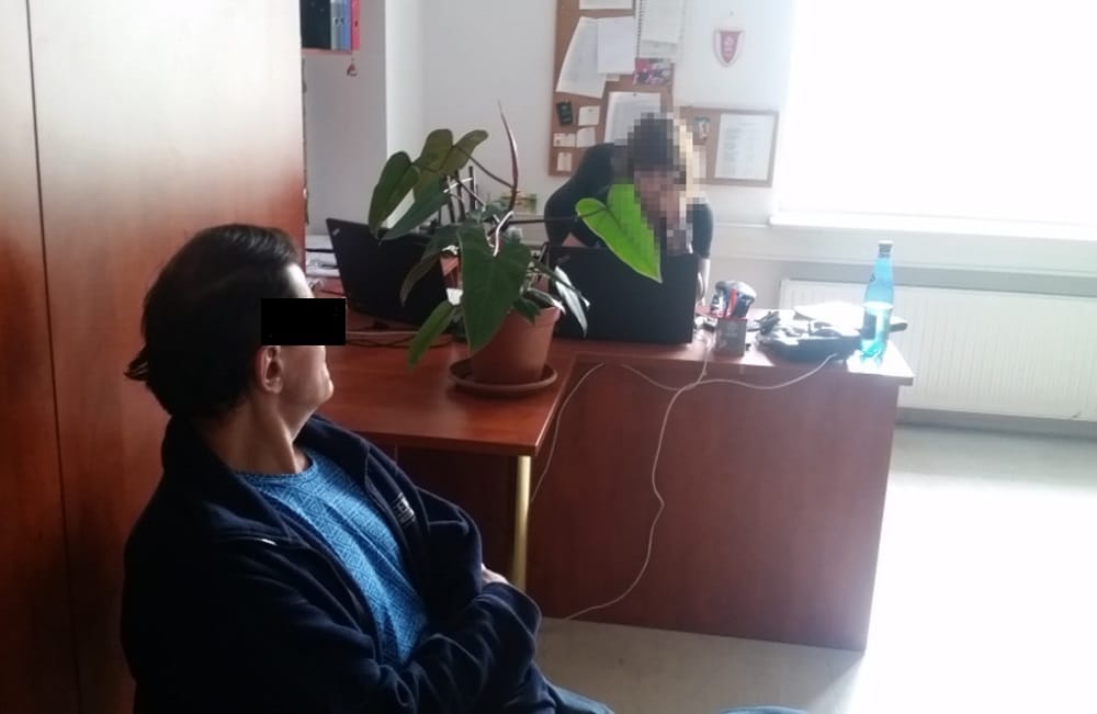 Dwie osoby pracujące przy biurkach w biurze z rośliną.