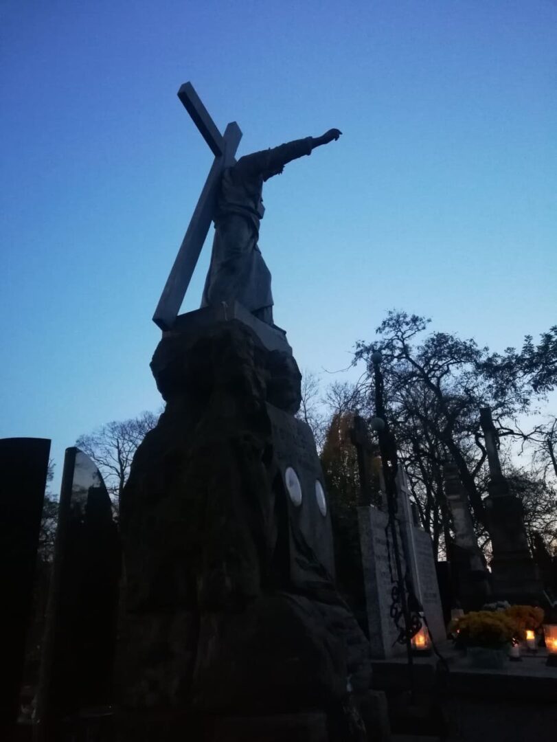 Sylwetka Jezusa niosącego krzyż o zmierzchu na cmentarzu