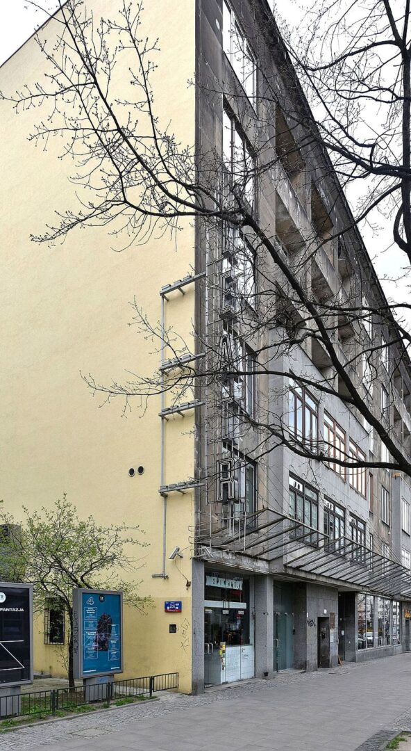 Nowoczesny budynek z żółtą fasadą i dużymi oknami. Widoczny napis „Teatr”.