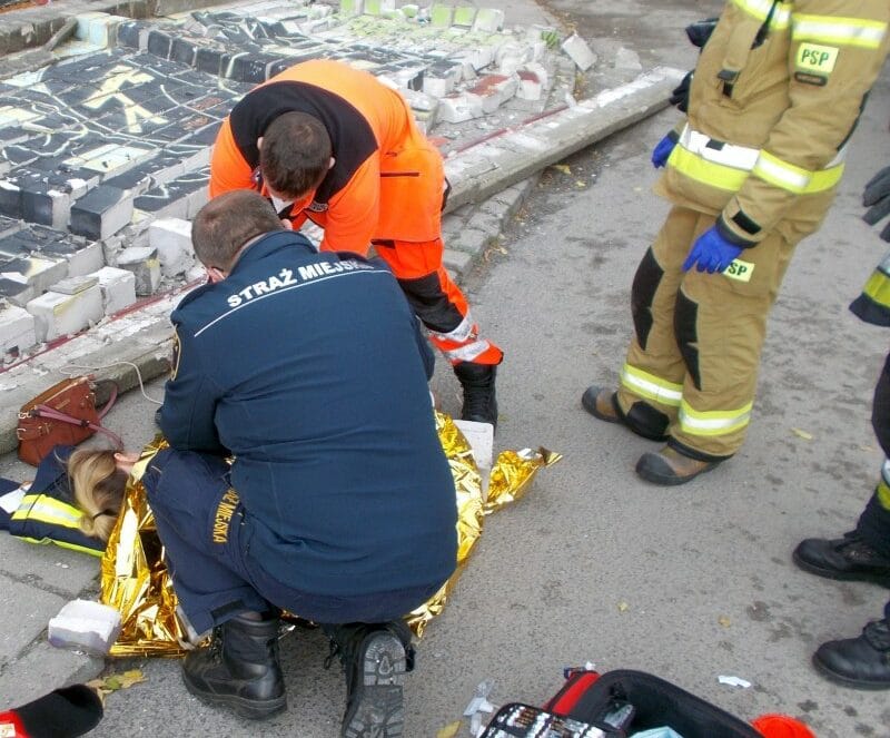 Ratownicy medyczni udzielają pierwszej pomocy osobie rannej na ziemi.