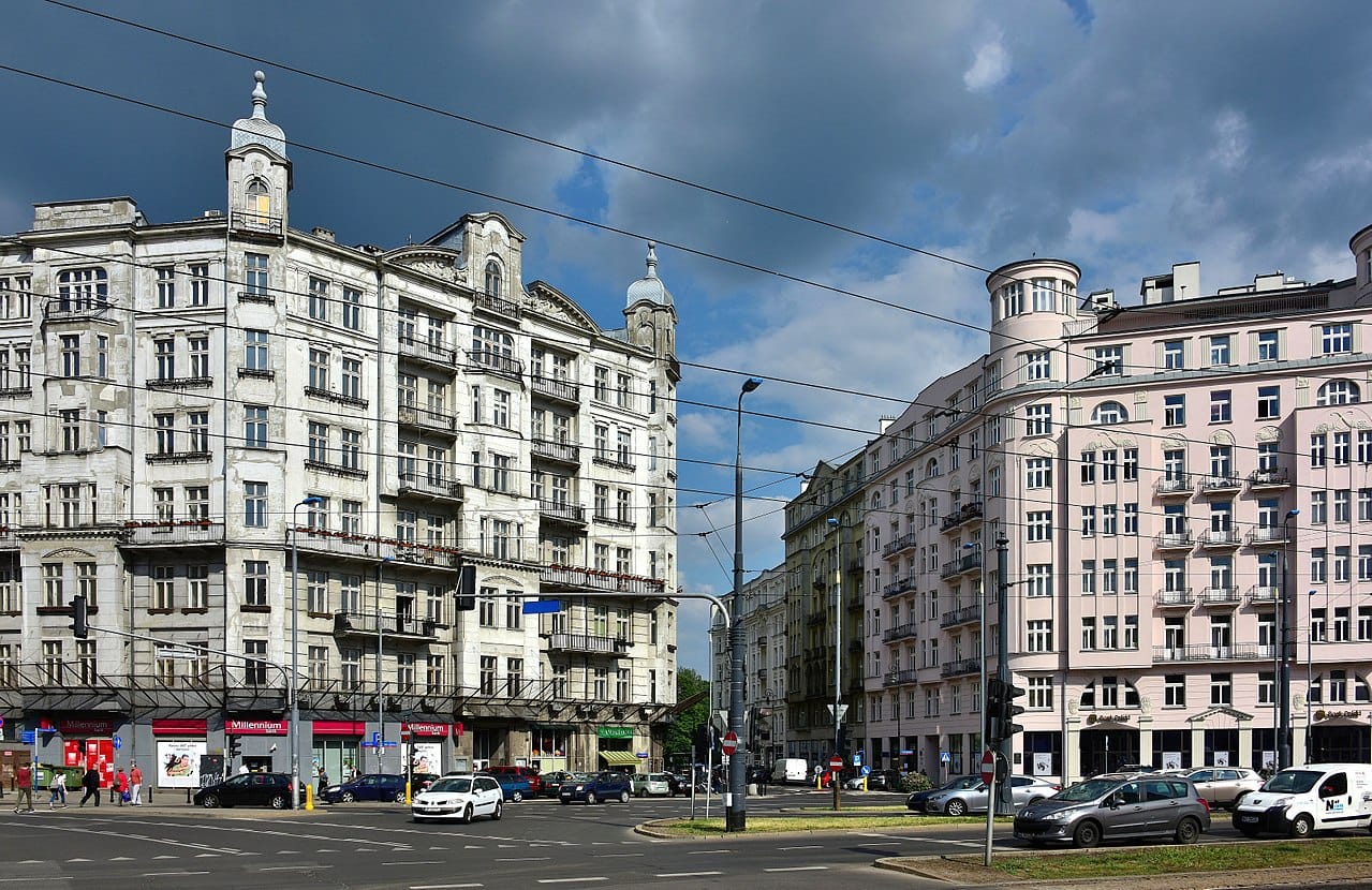 Widok na ulicę Warszawy: dwa budynki w stylu art déco przy ruchliwym skrzyżowaniu.