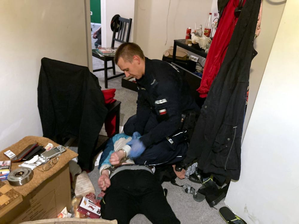 Policjant aresztujący podejrzanego z kajdankami na rękach.
