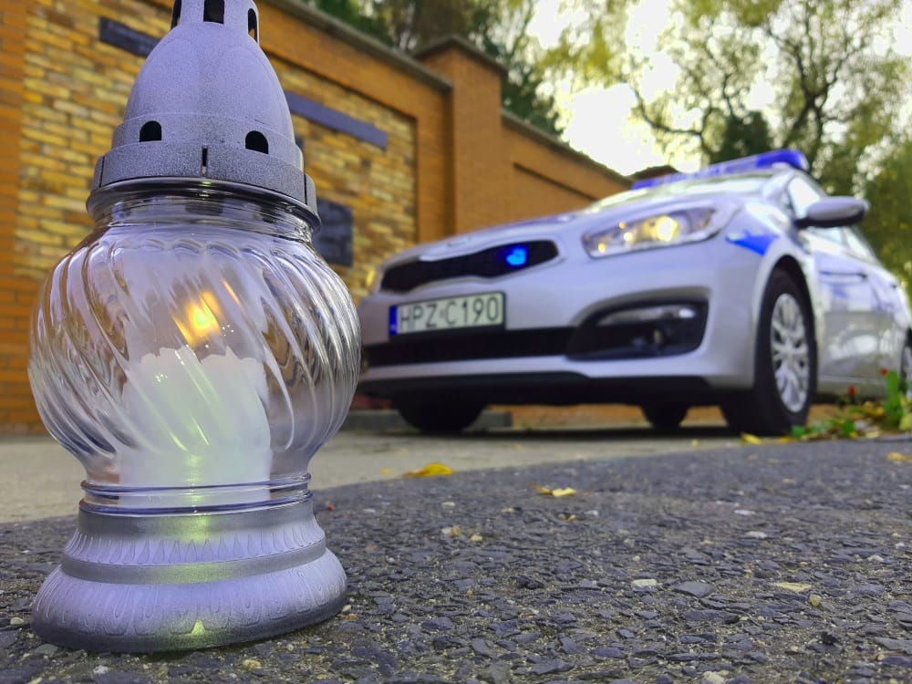 Zapalona świeca i rozmazany radiowóz przy ceglanym murze