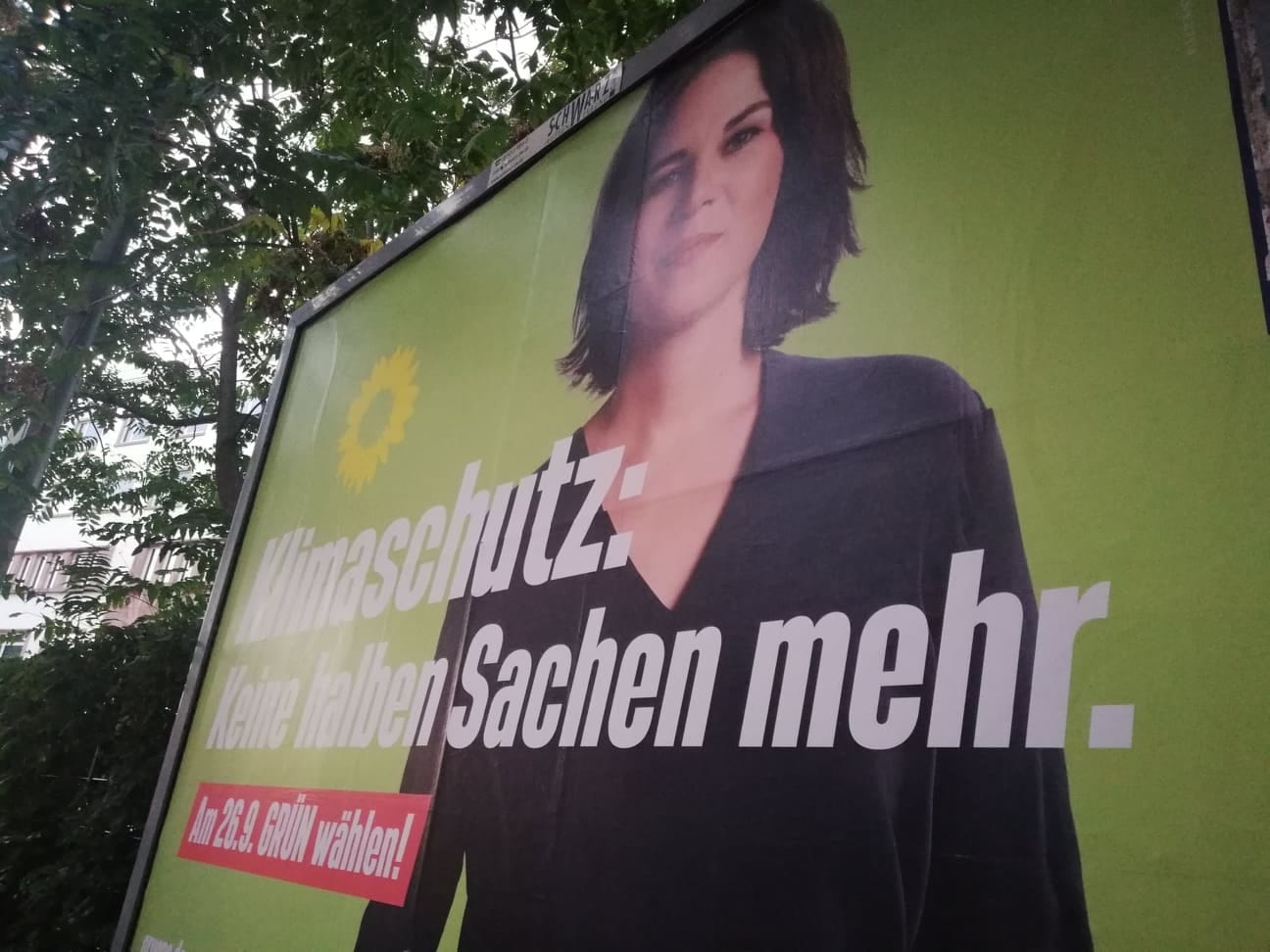 Billboard wyborczy z kobietą, tekstem „Klimaschutz: Keine halben Sachen mehr” i logo słonecznika. Zagłosuj na Zielonych 26 września.