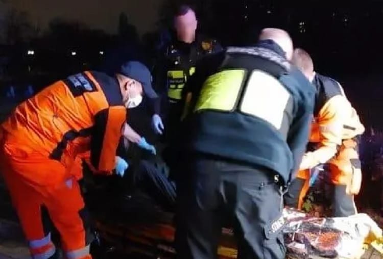 Ratownicy medyczni udzielają pomocy pacjentowi na noszach w nocy.