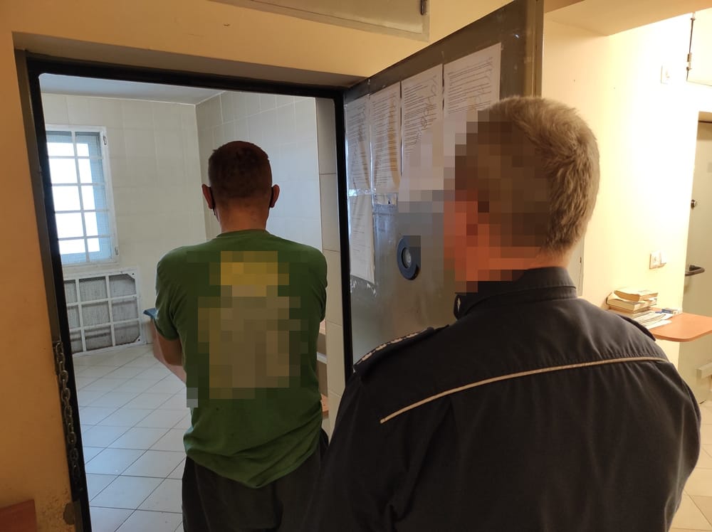 Więzień eskortowany przez policjanta do celi.