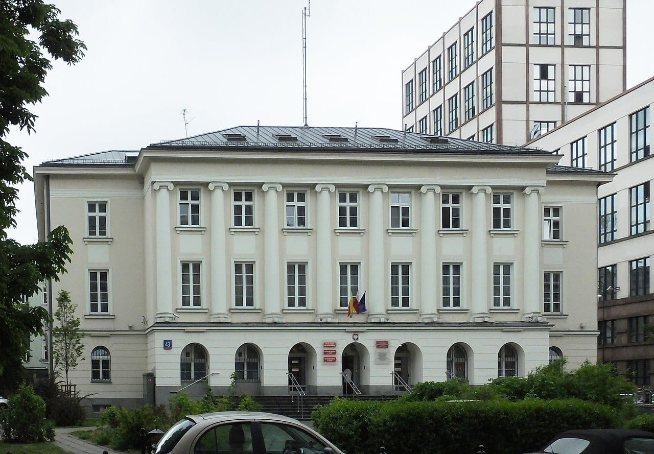 Budynek w stylu klasycznym z kolumnami, widoczna flaga rumuńska