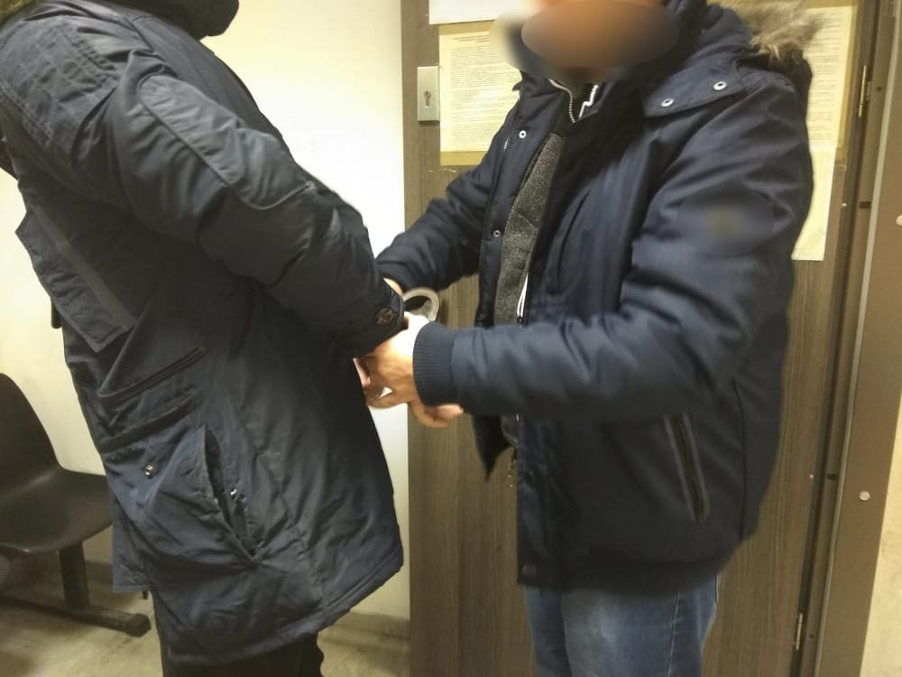 Policjant zakłada podejrzanemu kajdanki podczas aresztowania.