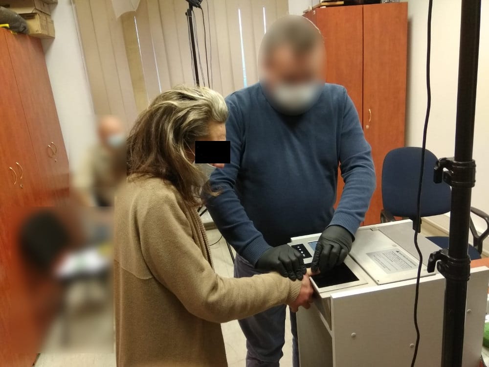 Dwie osoby korzystające ze skanera linii papilarnych w trakcie procesu rejestracji danych biometrycznych.