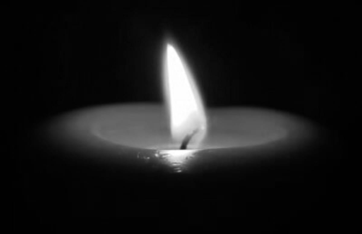 Pojedynczy płomień świecy płonący jasno w ciemności.