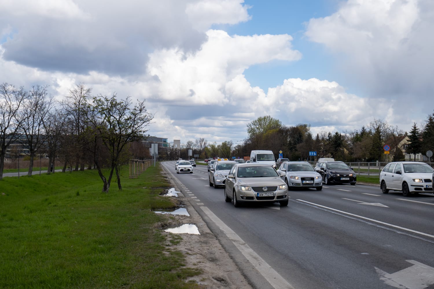 Samochody jadące ulicą miasta pod zachmurzonym niebem.