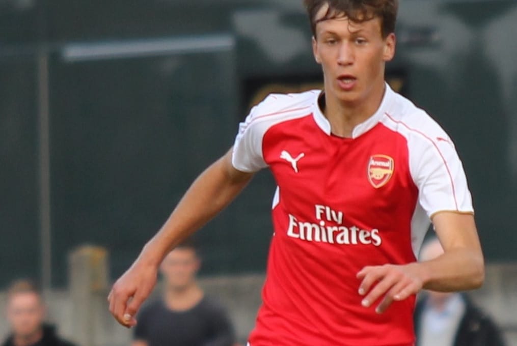 Młody piłkarz Arsenalu w akcji, ubrany w czerwoną koszulkę Fly Emirates.