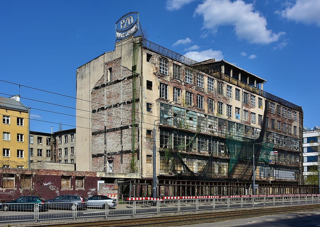 Opuszczony budynek fabryczny z tabliczką „PZ0 Warszava”, świadczącą o rozpadzie miasta i historii przemysłu.