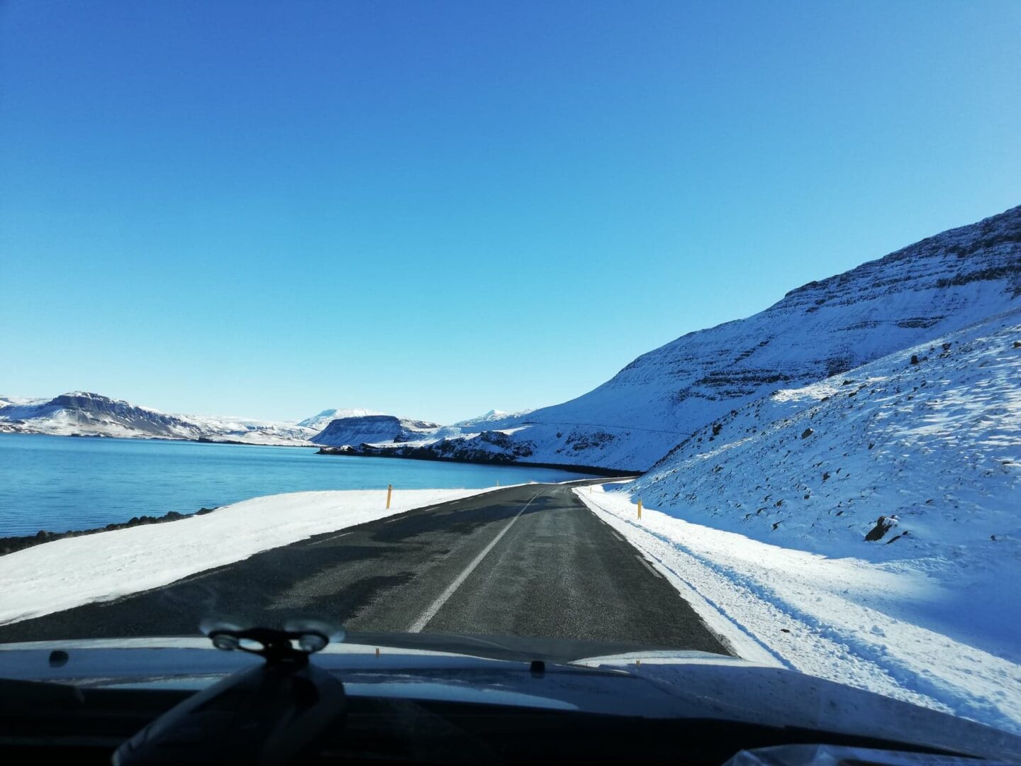 Malownicza zimowa wycieczka samochodowa po Islandii: ośnieżone góry i fiord.