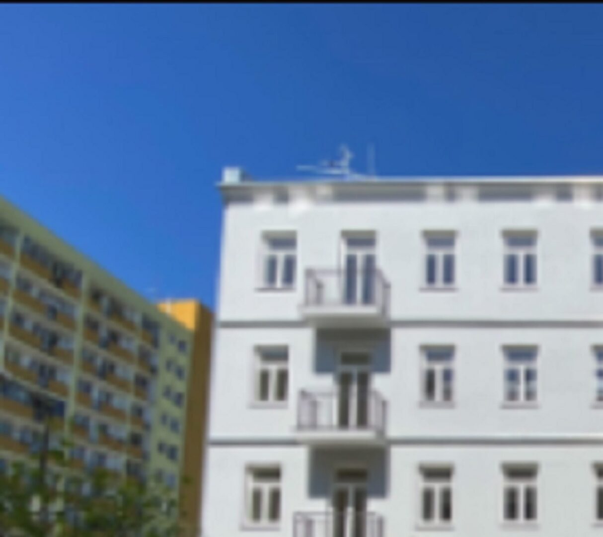 Nowoczesny budynek apartamentowy z balkonami pod czystym, błękitnym niebem.