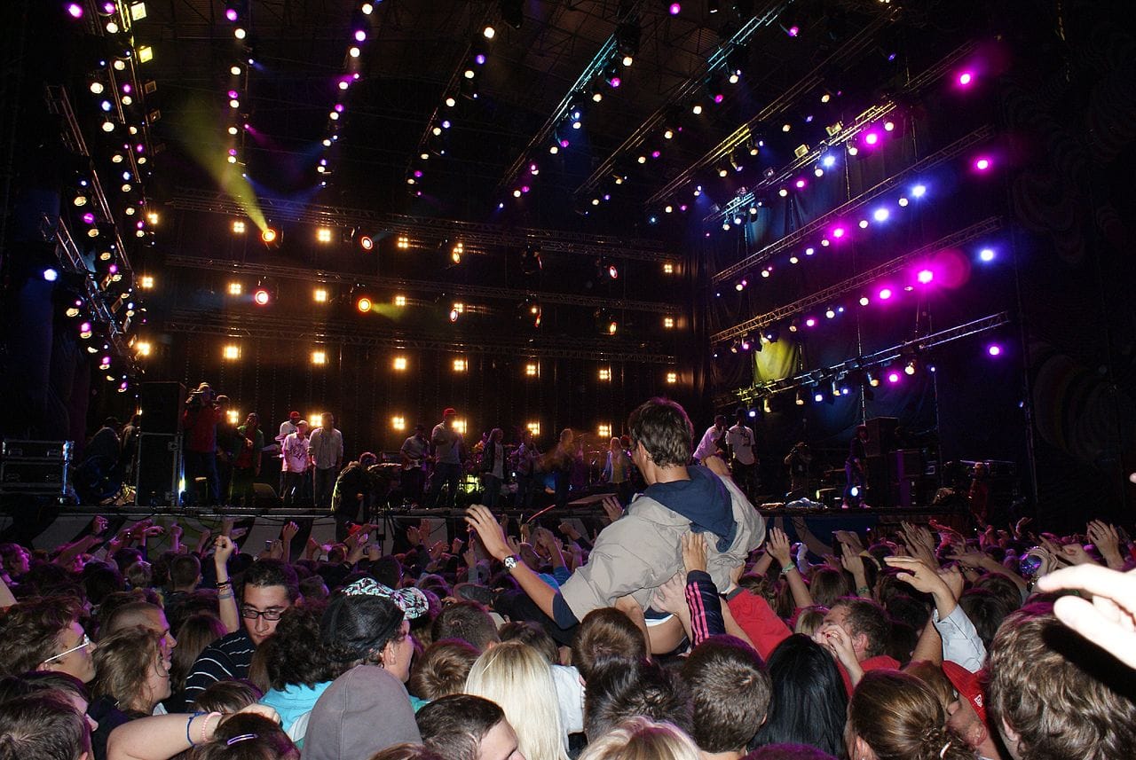 Tłum na koncercie wiwatuje, a publiczność podnosi mężczyznę.