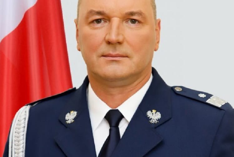 Komendant Policji Polskiej w mundurze, w tle polska flaga
