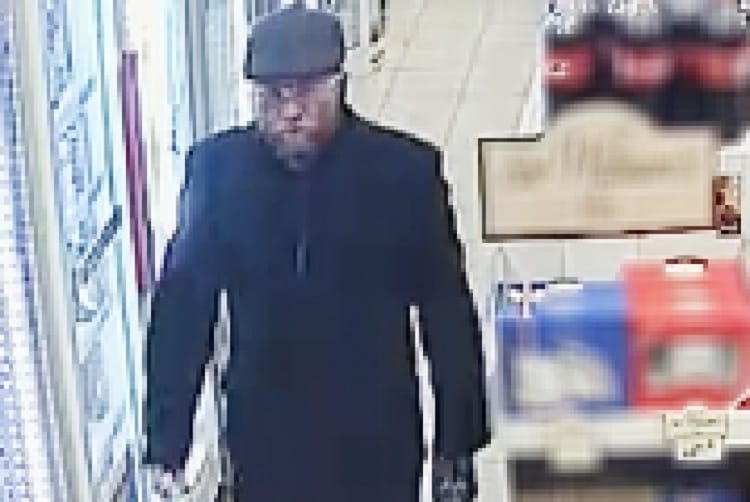 Obraz z monitoringu przedstawia mężczyznę ubranego w ciemny płaszcz i czapkę, prawdopodobnie biorącego udział w napadzie.