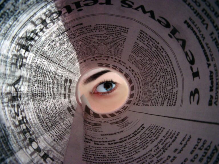 Oko patrzące przez tunel gazety; widoczny nagłówek „Wiadomości”.