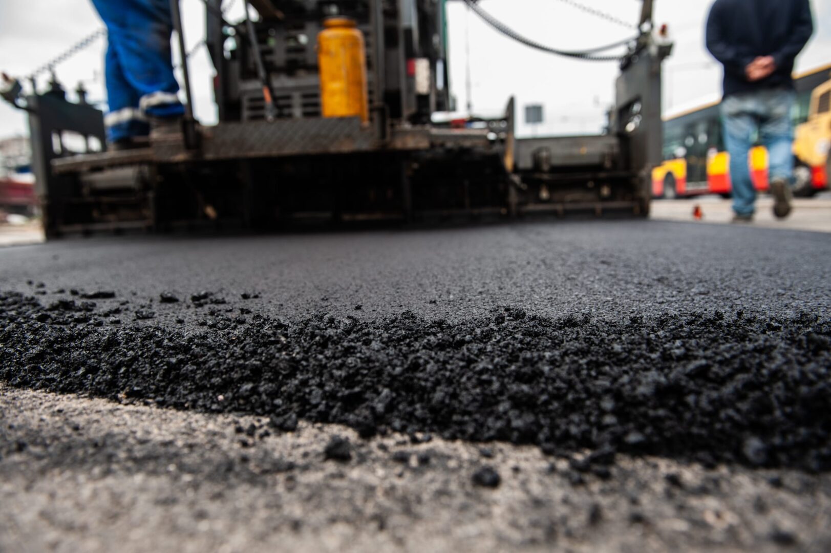 Maszyna układająca świeży asfalt na drodze.