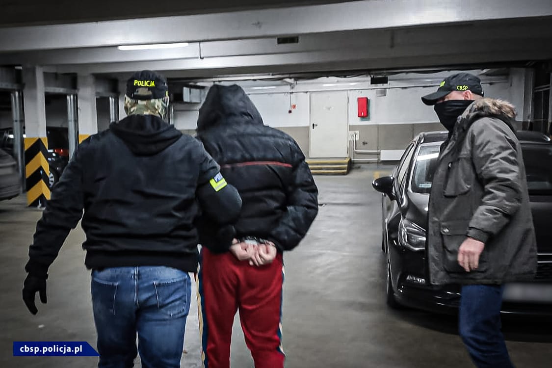 Policjanci zatrzymują podejrzanego na parkingu.