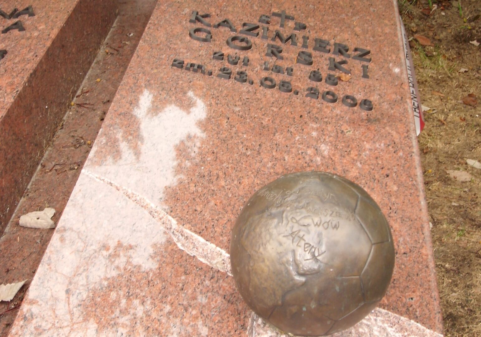 Nagrobek Kazimierza Górskiego z brązową piłką nożną. Daty 1921-2006.